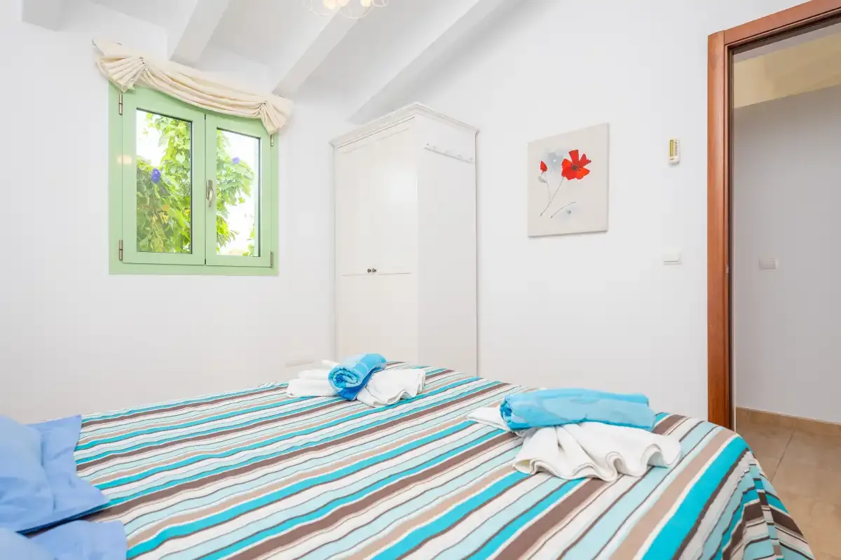A bedroom with striped bedding and a green-framed window.