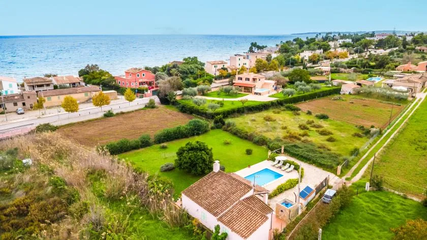 Aerial view of a coastal neighborhood with homes, gardens, and the sea.
