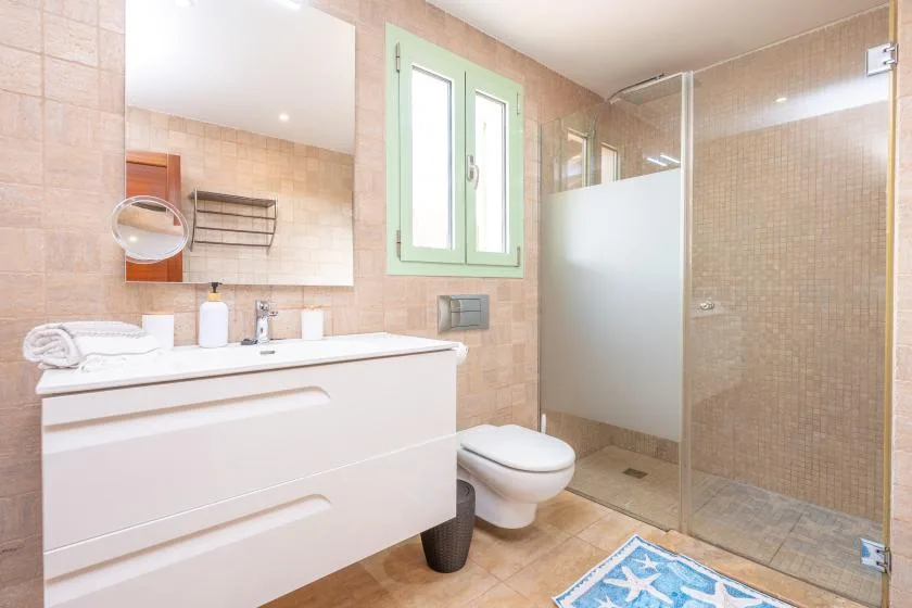 A tiled bathroom with a vanity, toilet, and glass shower.