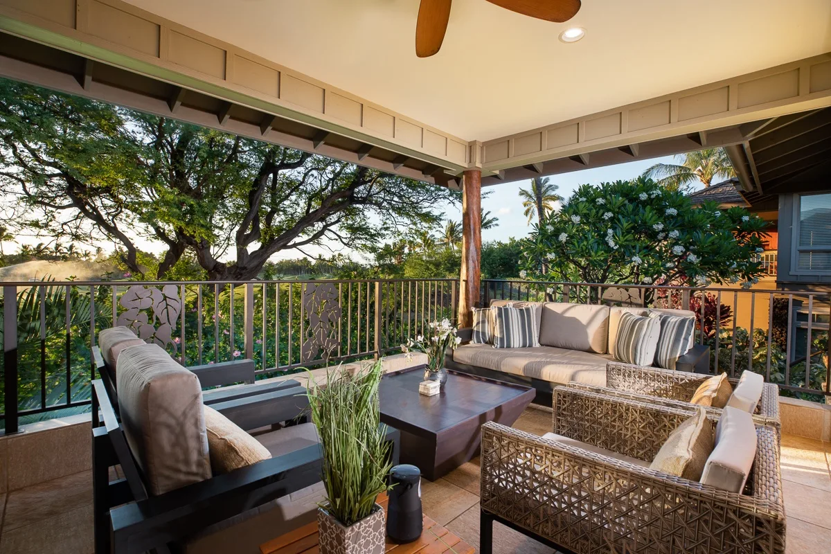 A covered outdoor seating area overlooks leafy trees and tropical plants.