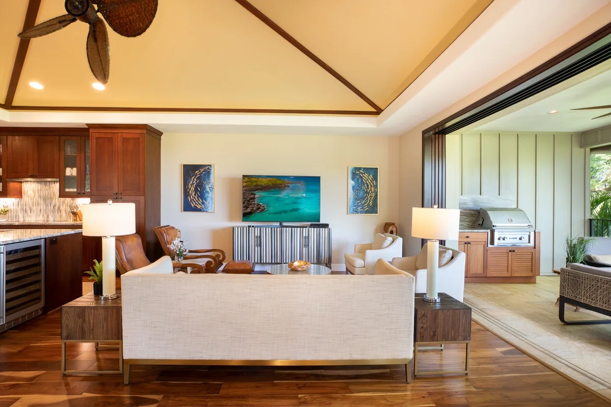 A living room with seating, a television, and an open kitchen area.