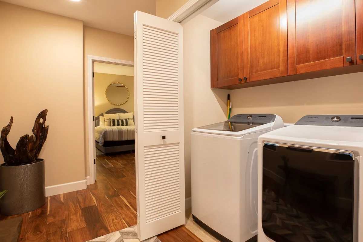 A laundry room with a washer and dryer beneath wooden cabinets.