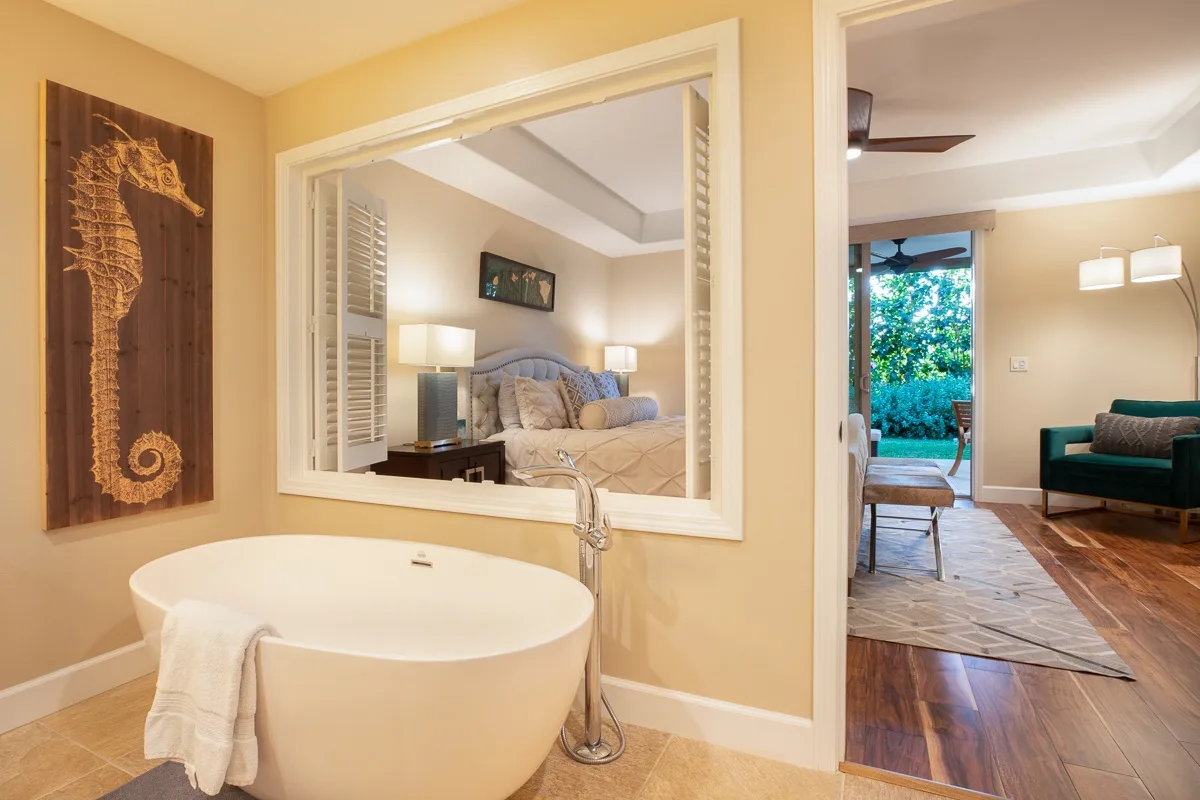 A bathroom with a freestanding tub overlooks a bedroom and sitting area.