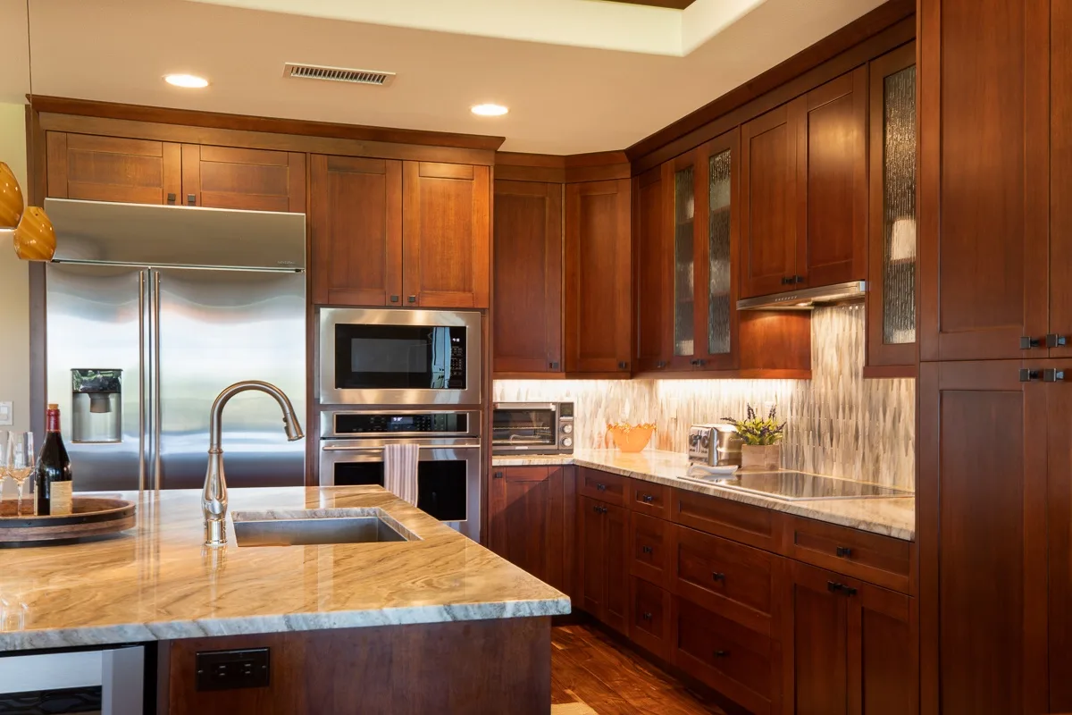 A spacious kitchen with dark wood cabinets, stainless steel appliances, and a stone island.