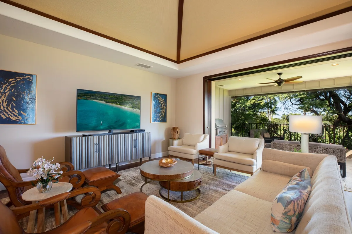 A bright living room with seating arranged around a round coffee table and artwork on the walls.