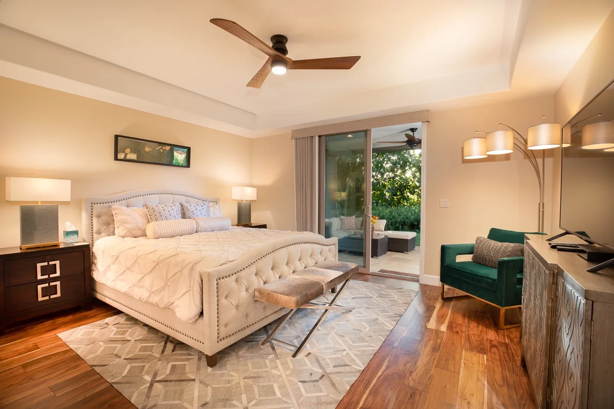 A bedroom with a bed, a green armchair, and sliding glass doors to a patio.