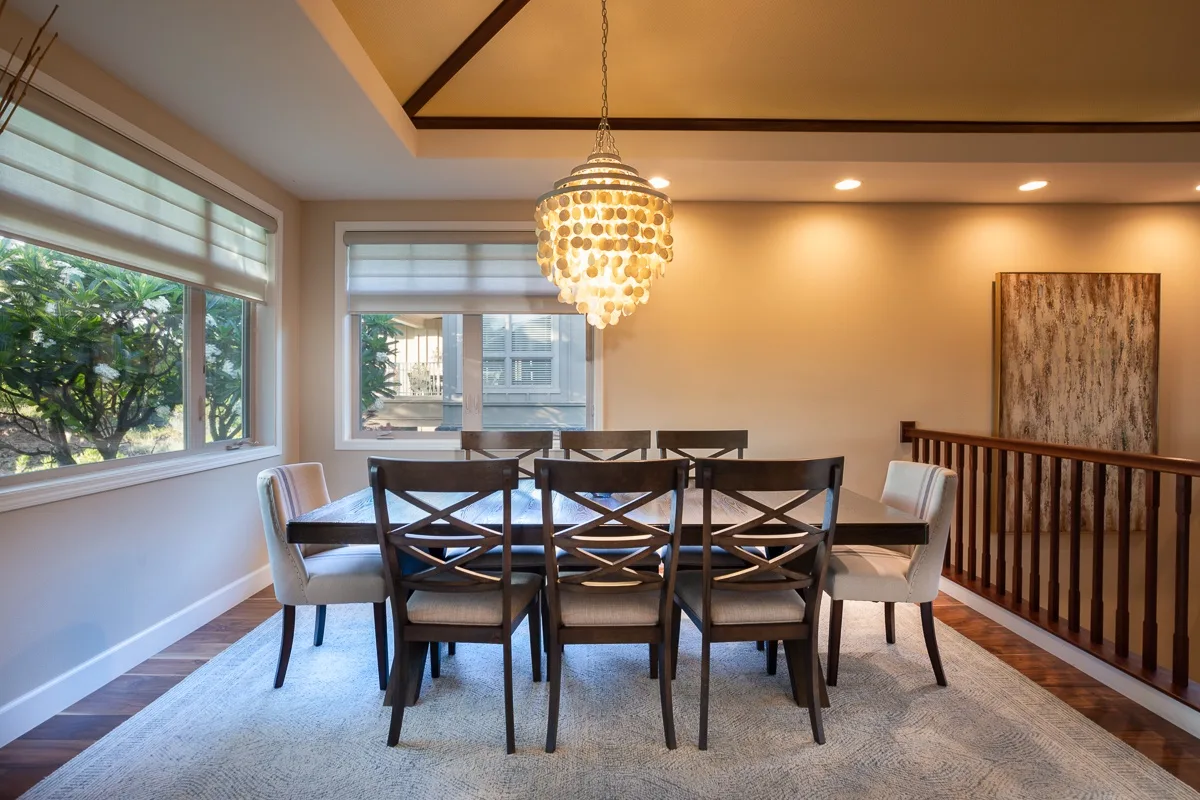 A dining area with a long table and chairs beneath a hanging light.