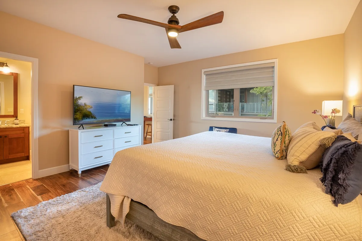 A bedroom with a large bed, a television on a dresser, and a window.