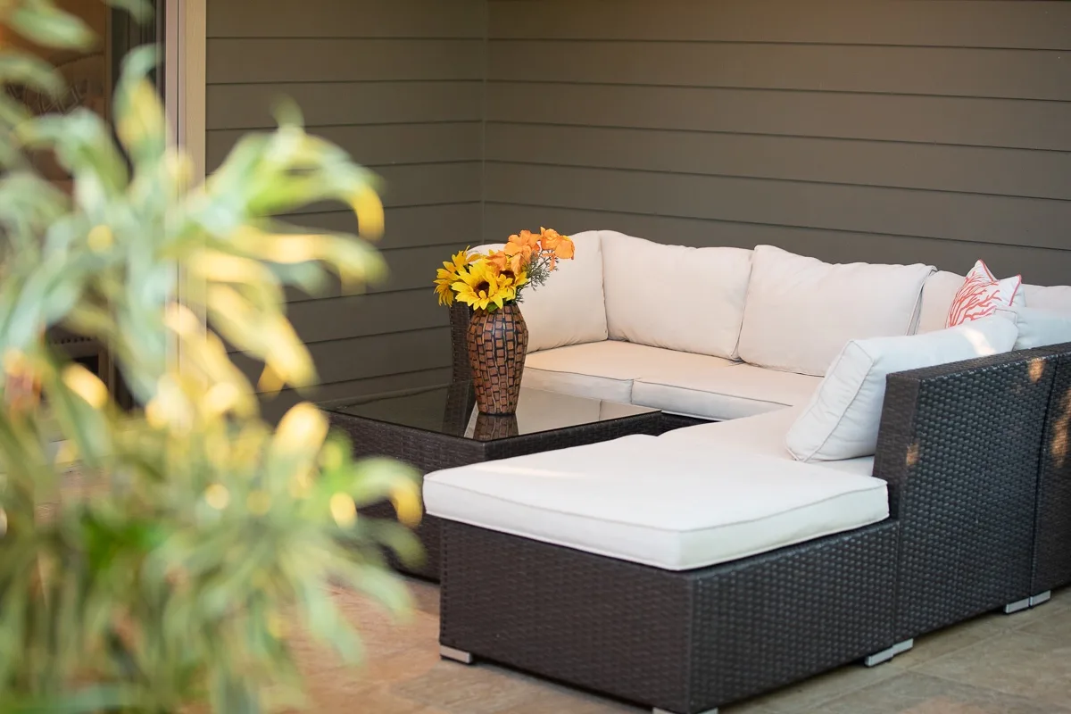 An outdoor seating area with a sectional and a vase of flowers.