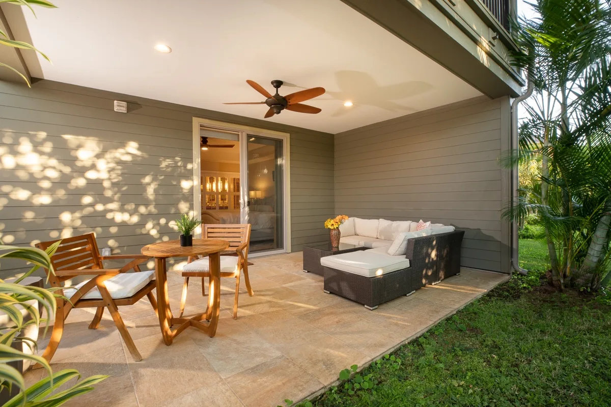 A covered patio with outdoor seating and a table beside a sliding glass door.