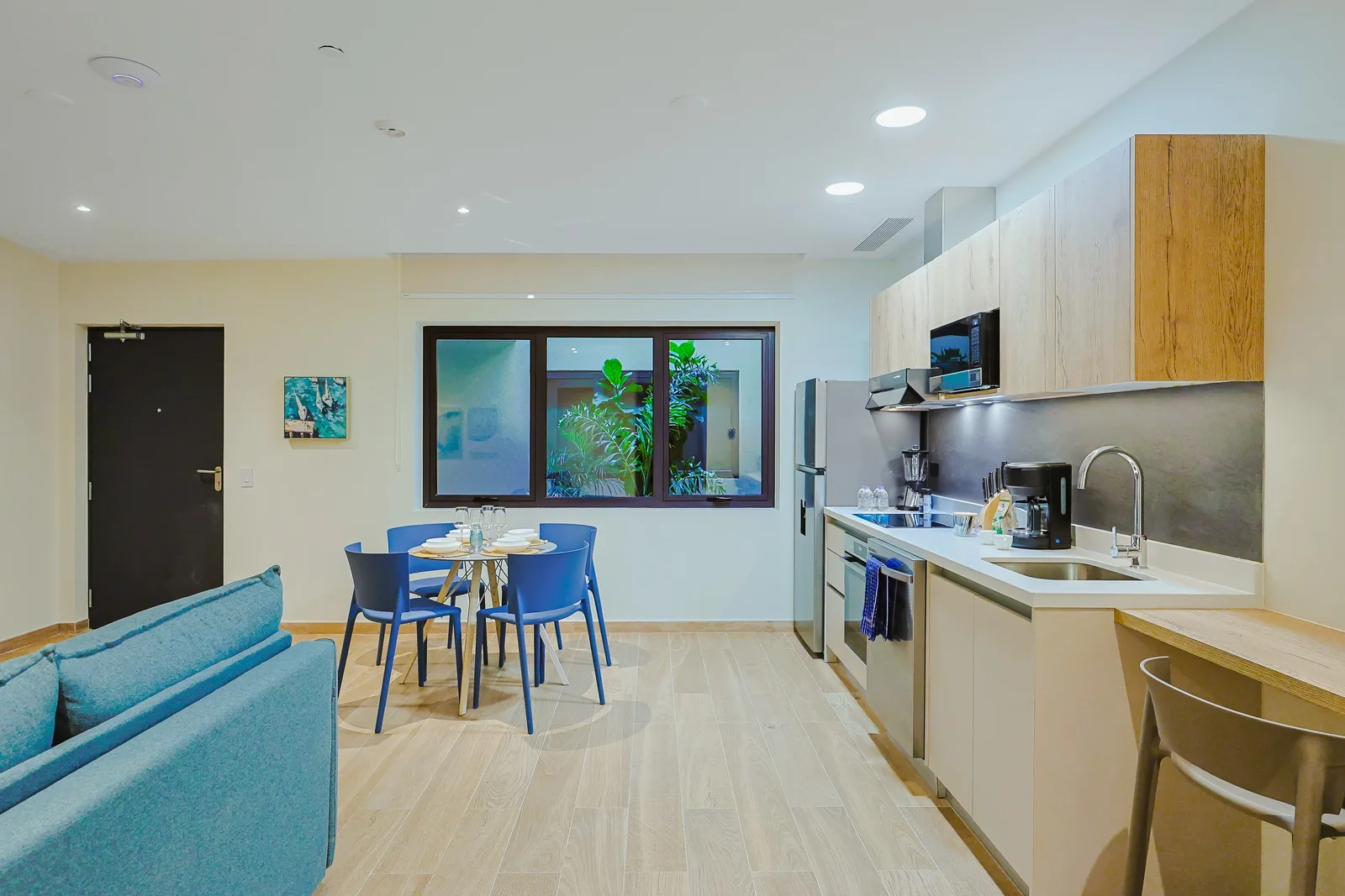 Open-concept living space with modern kitchen, stainless appliances, and light wood floors. Cozy dining nook and abundant natural light make it perfect for relaxing and gathering.