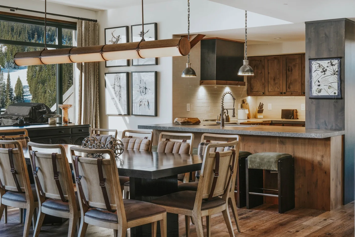 An open kitchen and dining area with a long table and pendant lights.
