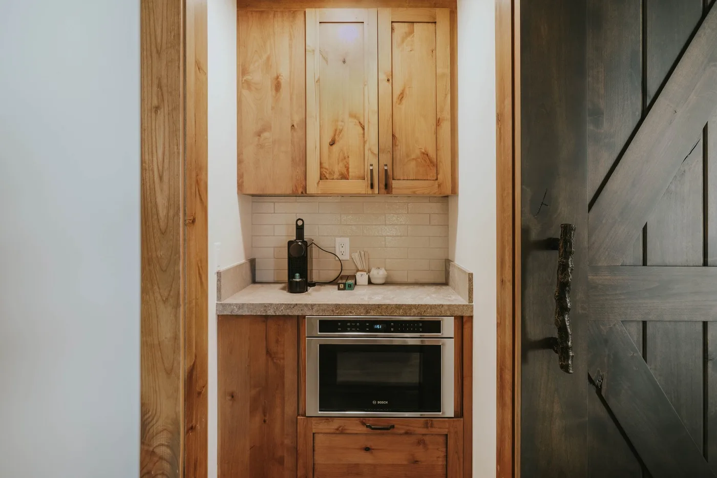 A compact kitchen nook with wooden cabinets, a countertop, and a built-in oven.