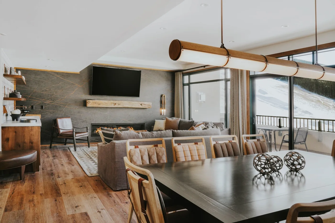 A living and dining area with seating, a television, and large windows.