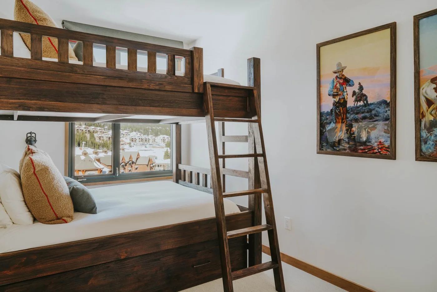 A bedroom with a dark wooden bunk bed and framed artwork on the wall.