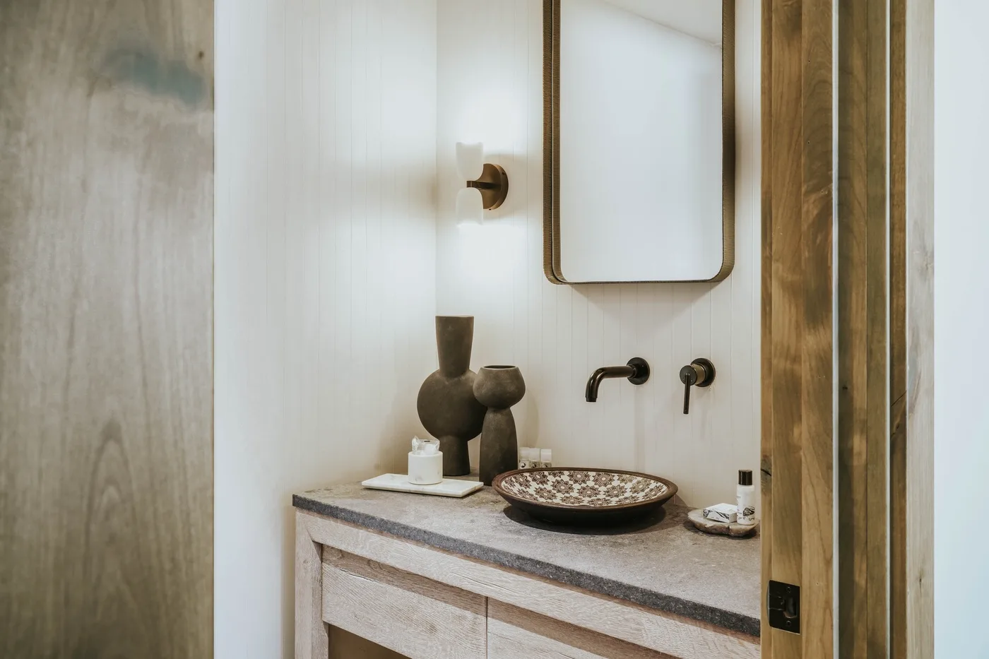 Bathroom vanity with a mirror, wall-mounted fixtures, and a decorative bowl.