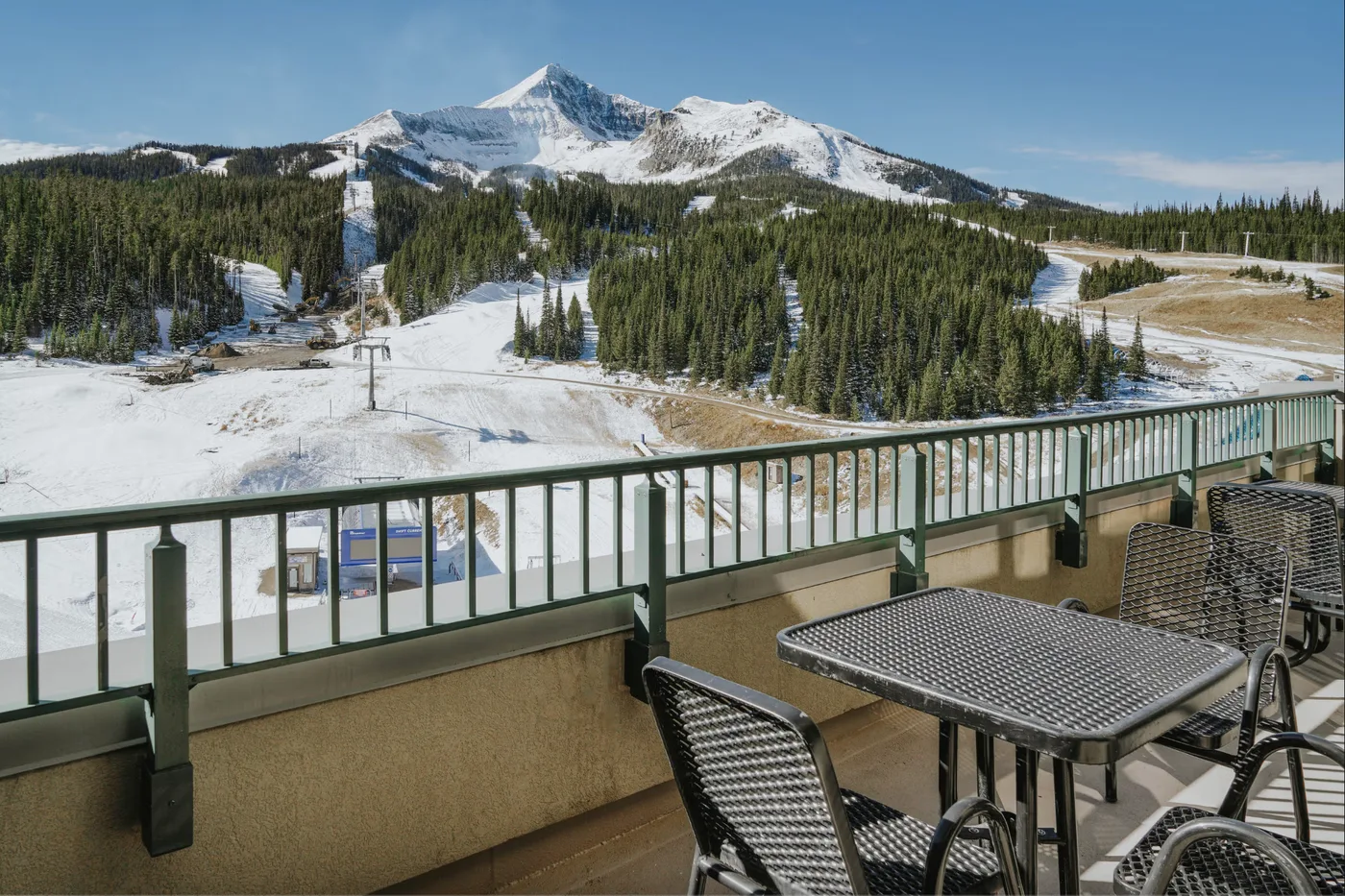 A patio overlooks a snowy mountain and forested ski slopes.