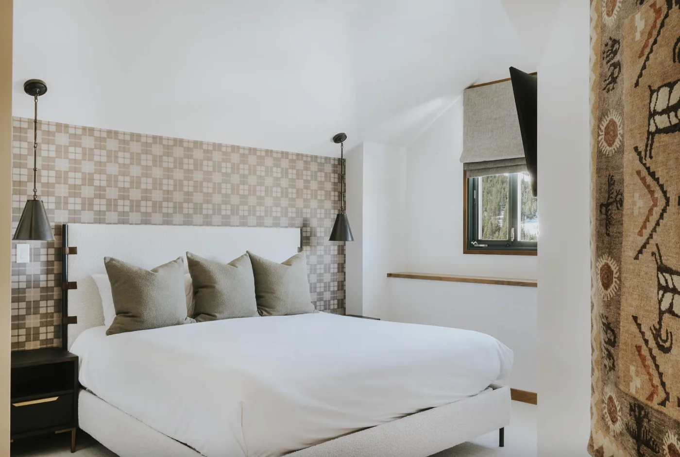 A bedroom with a white bed and patterned wall behind the headboard.