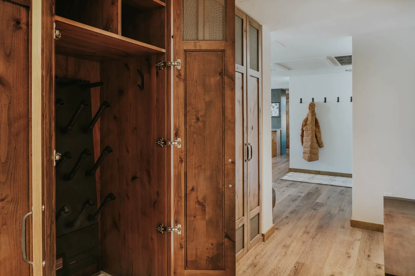 A wood-paneled entry hall opens onto a bright hallway with a coat hanging on the wall.