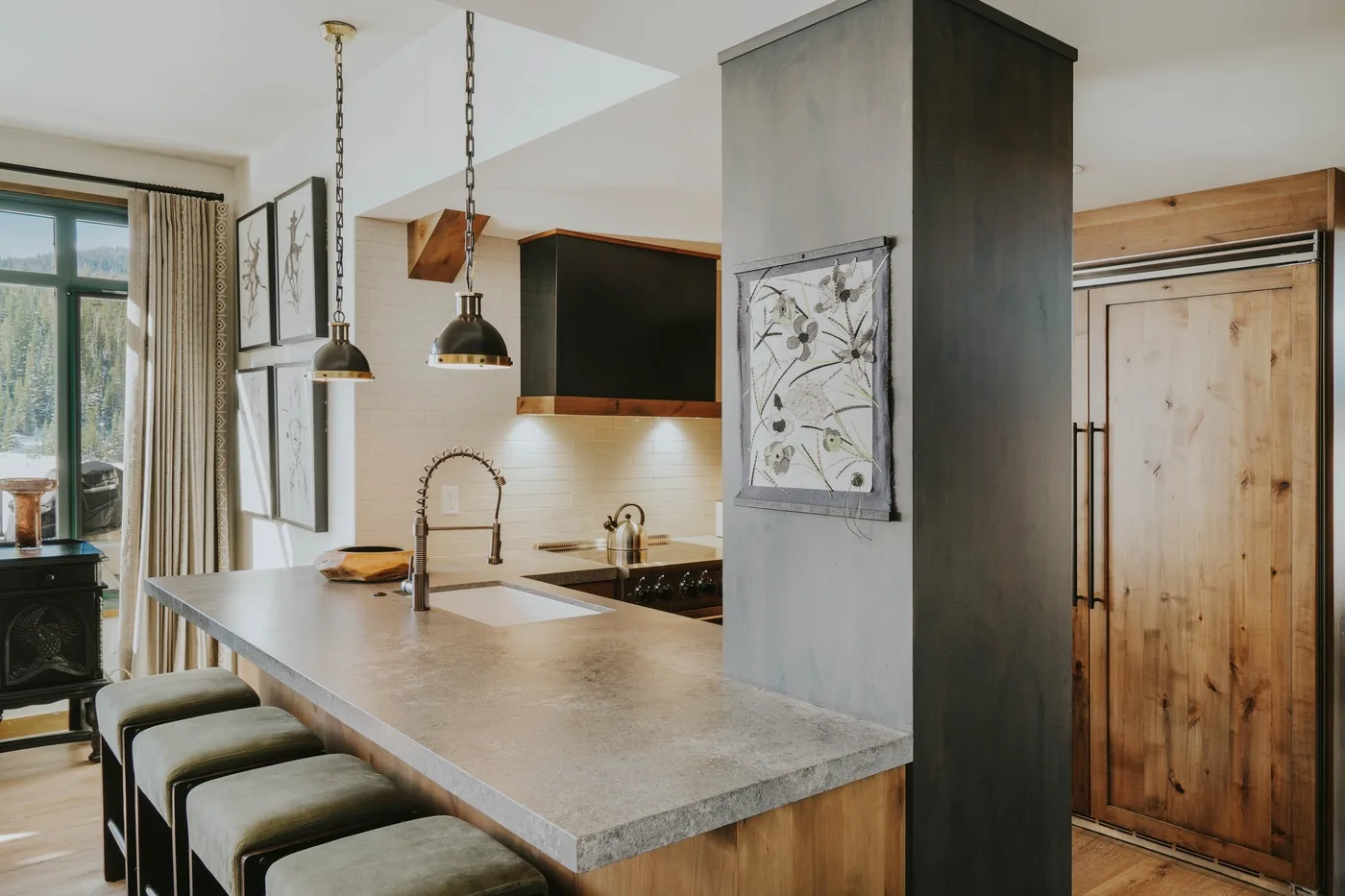 An open kitchen with a long island, pendant lights, and wood cabinetry.