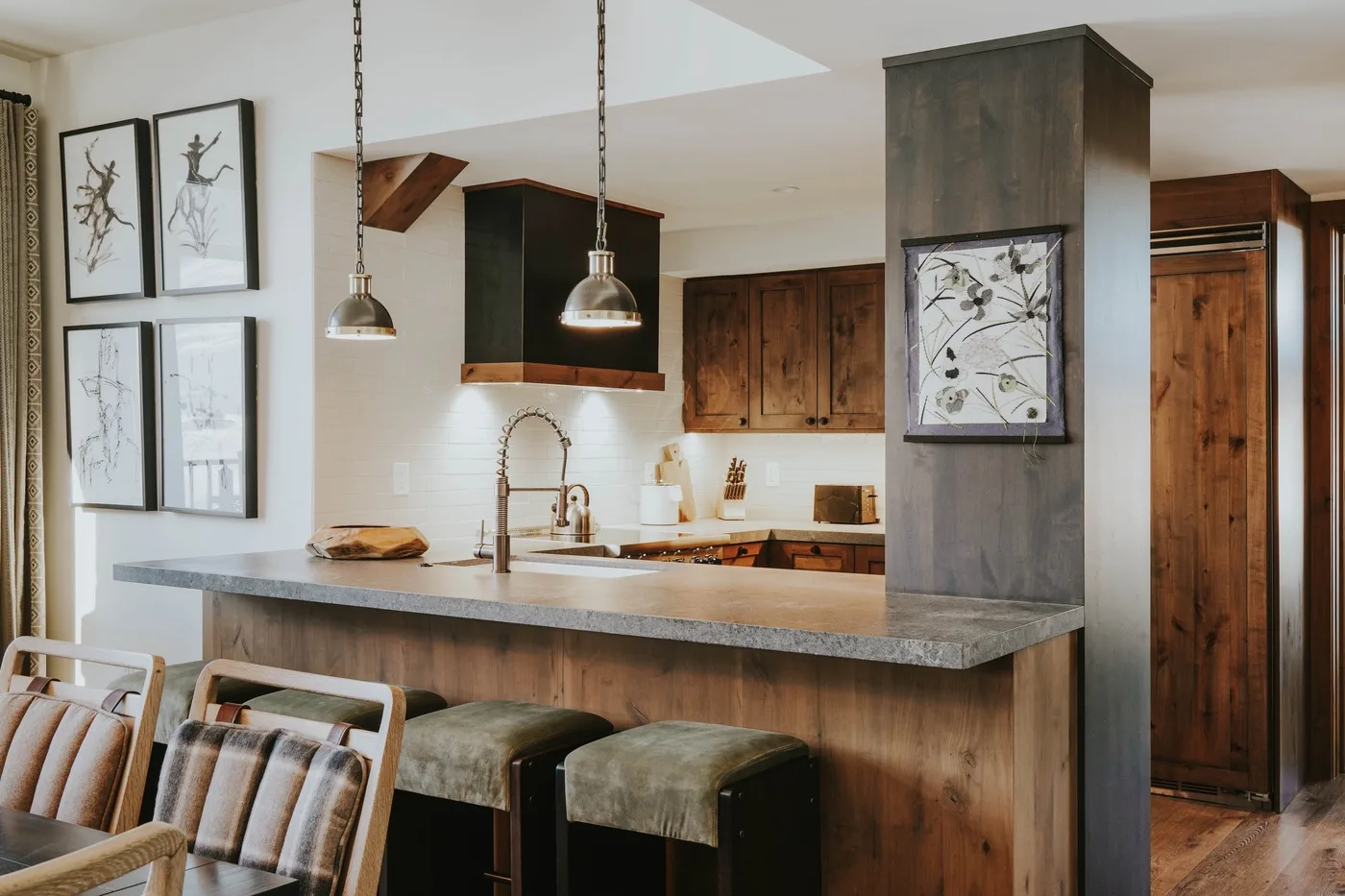 A kitchen with a broad island, wooden cabinets, and pendant lights.
