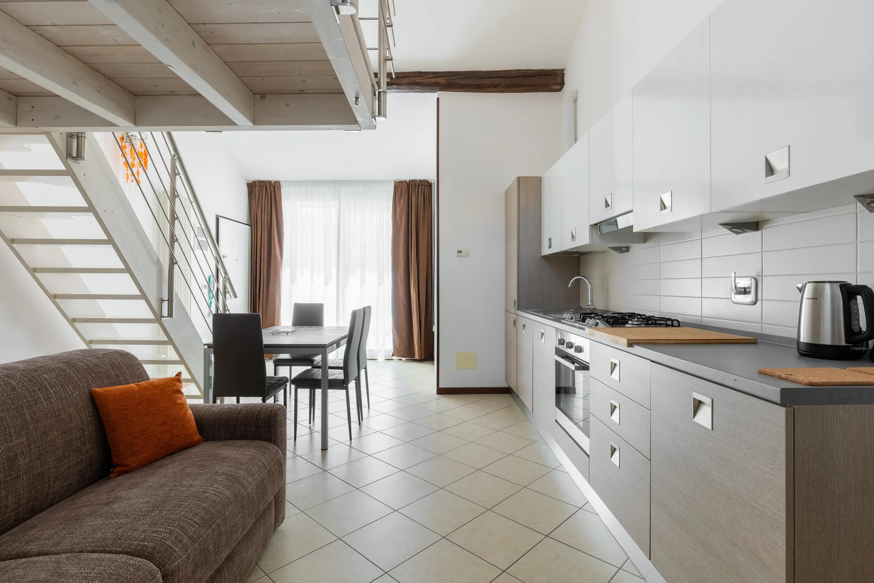 Una estancia diáfana y luminosa con cocina, mesa de comedor y zona de estar.