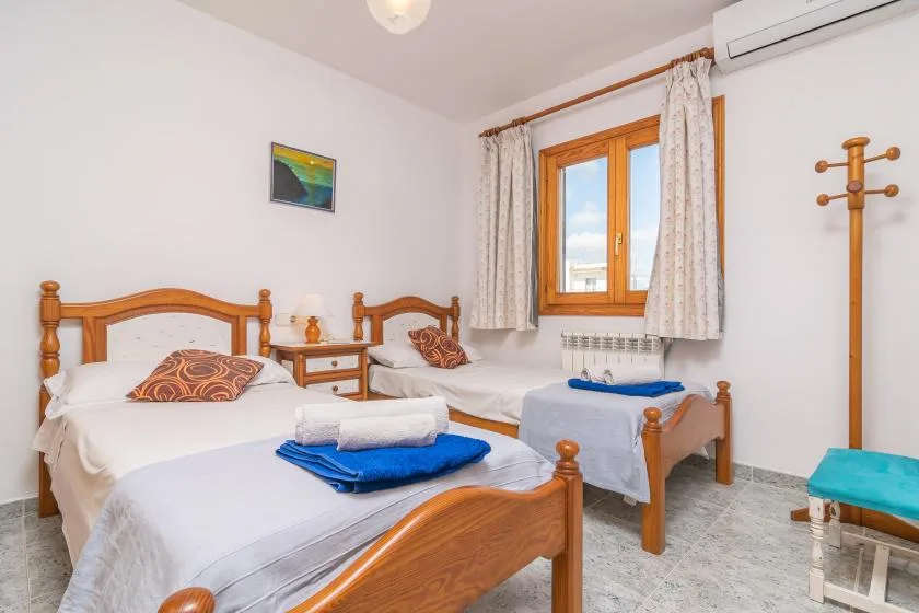 A bedroom with two single beds and a window with curtains.