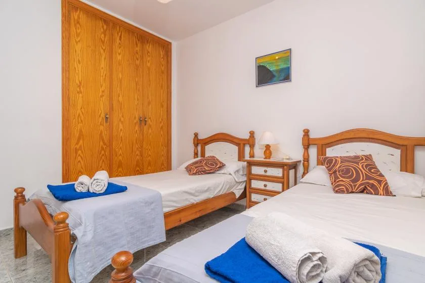 A bedroom with two beds, wooden headboards, and a wardrobe.