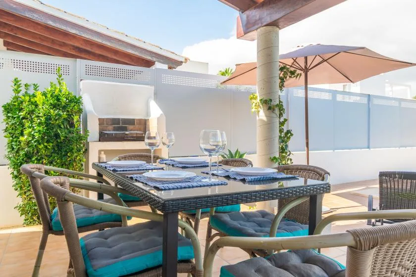 An outdoor dining area has a set table beneath a patio umbrella.