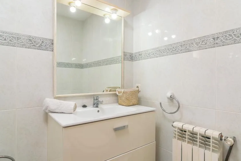 A bathroom vanity with a sink, mirror, and wall-mounted radiator.
