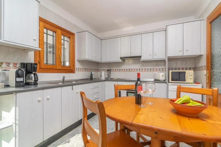 A bright kitchen with white cabinets and a wooden dining table.