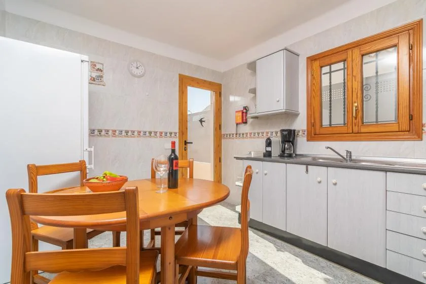 A kitchen and dining area with a wooden table and white cabinets.