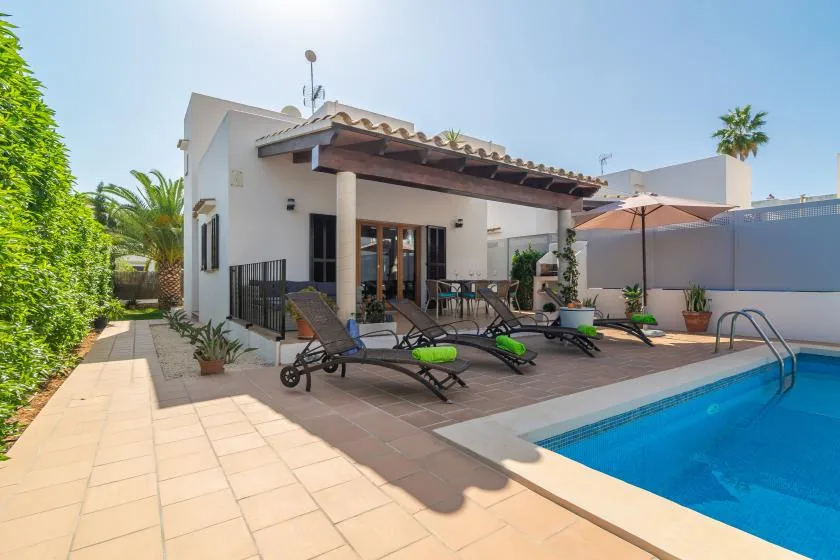 A sunny backyard patio with lounge seating beside a swimming pool.