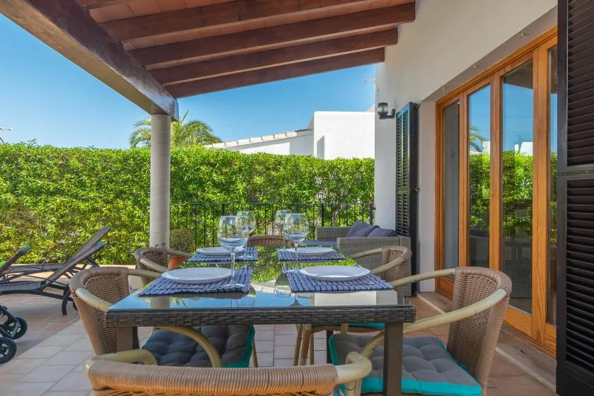 A covered outdoor dining patio with a set table beside large glass doors.