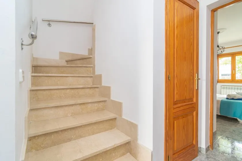 An indoor staircase beside a wooden door and an open doorway.
