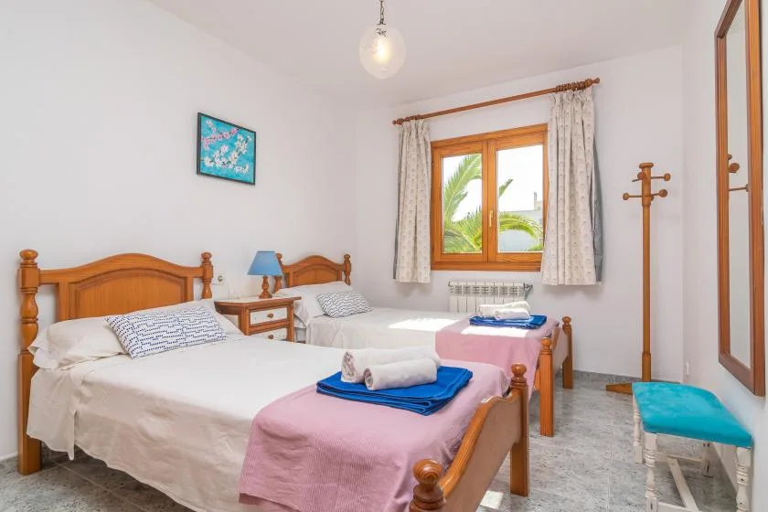 A bright bedroom with two single beds and a window with curtains.