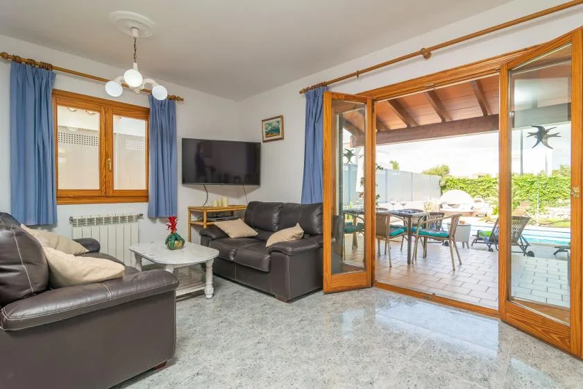A living room with seating and open glass doors leading to a sunny patio.