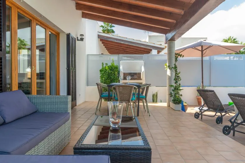 A tiled outdoor patio with a dining table, seating, and a large umbrella.