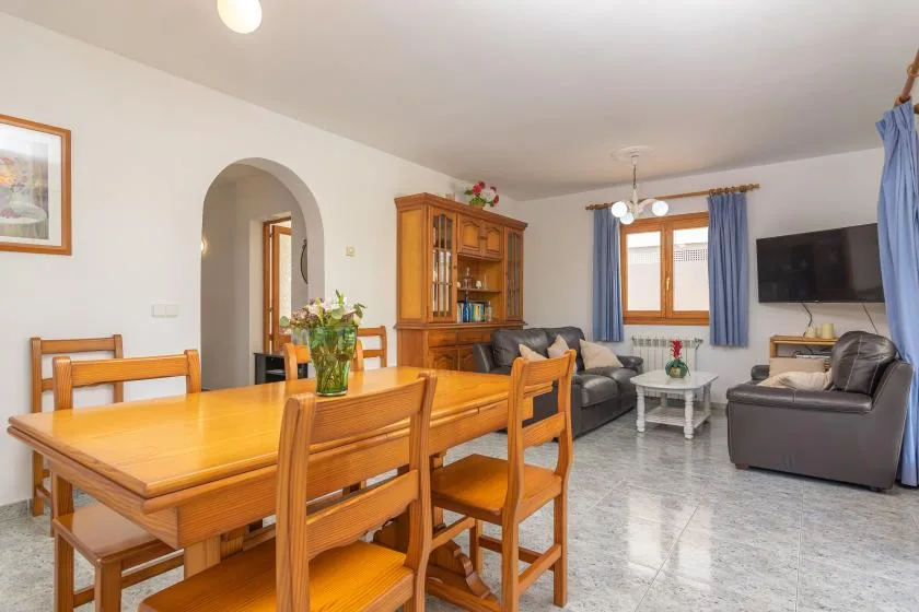 A living and dining room with wooden seating and a television.