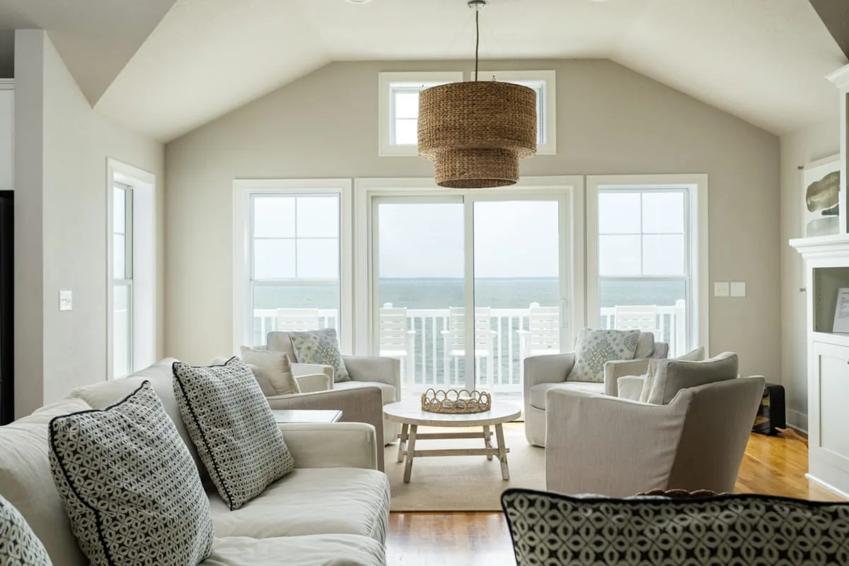 A bright living room has seating arranged around a low table beside large windows.