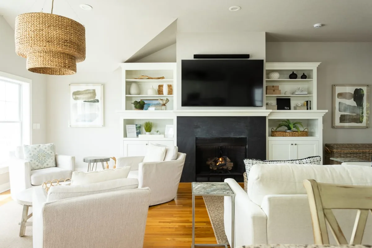 Una sala luminosa con asientos dispuestos alrededor de una chimenea y un televisor.