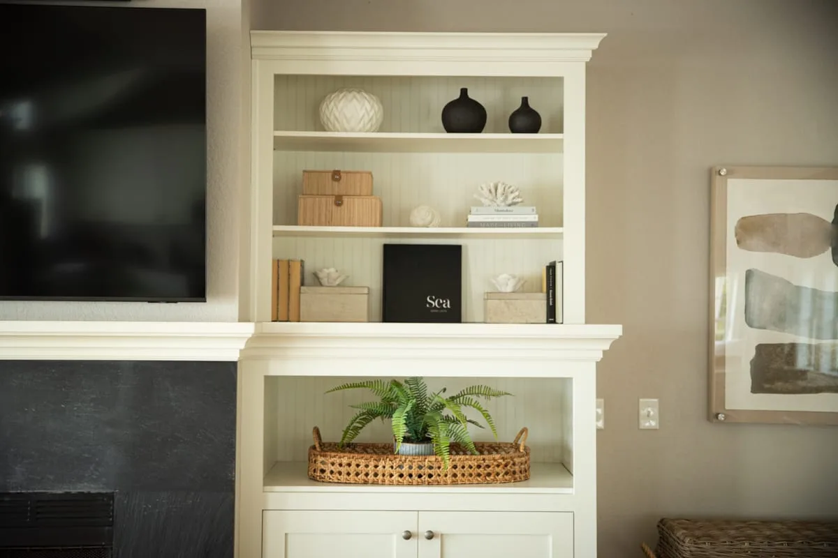 A living room wall features a television, fireplace, and built-in display shelves.