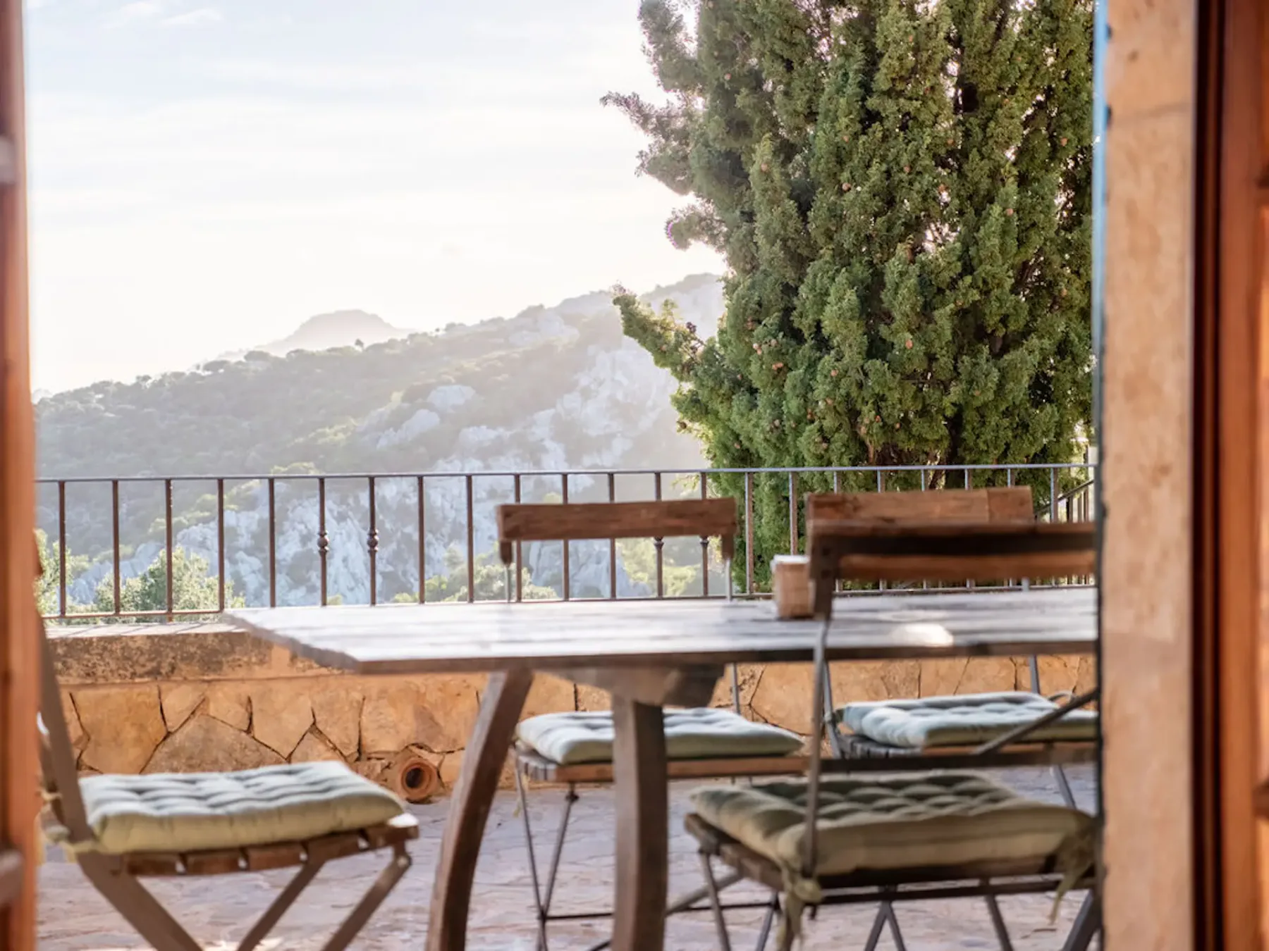 A mountain-view terrace with outdoor seating beside a tall tree.