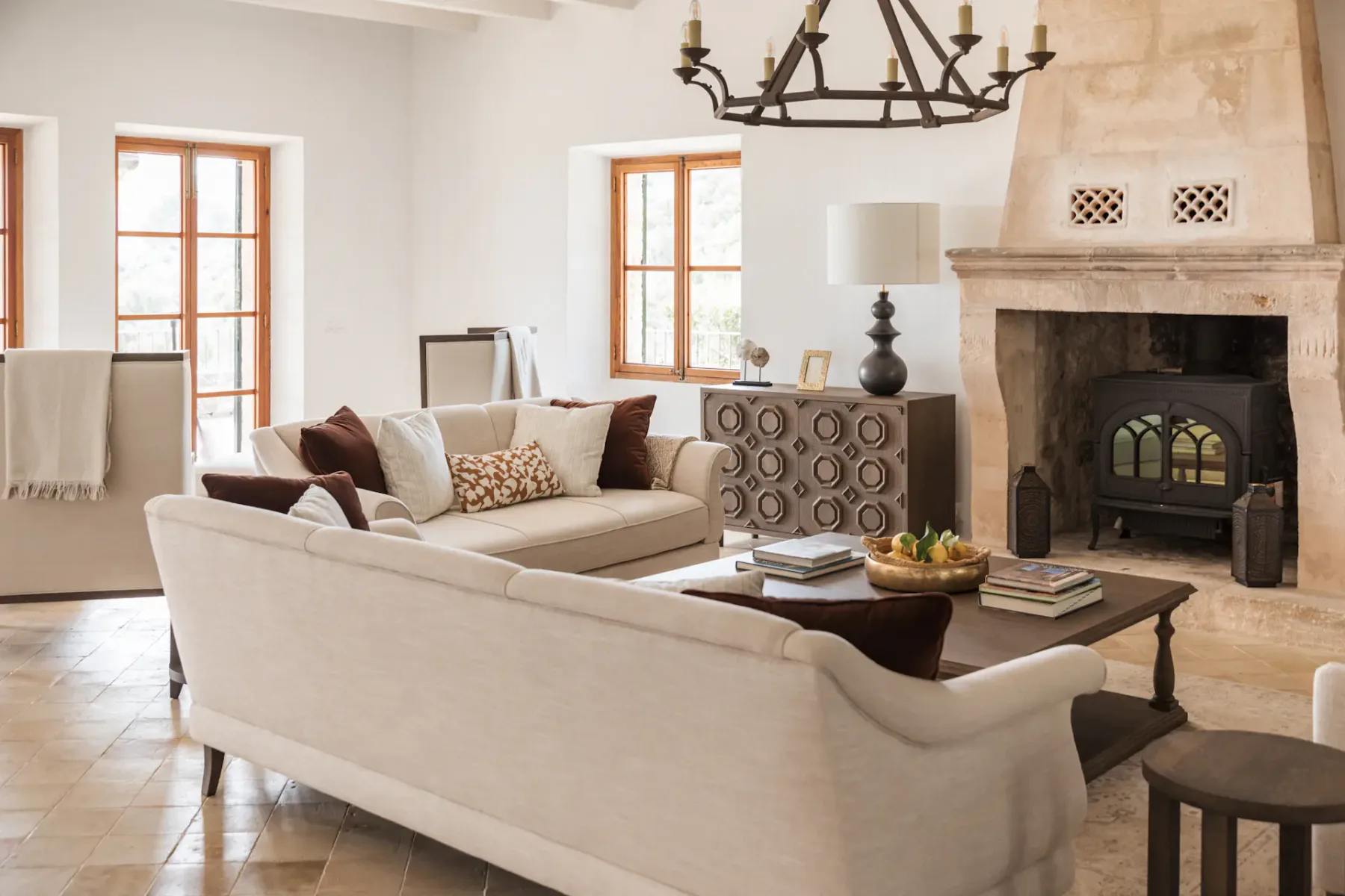 A bright living room with seating, a coffee table, and a large stone fireplace.