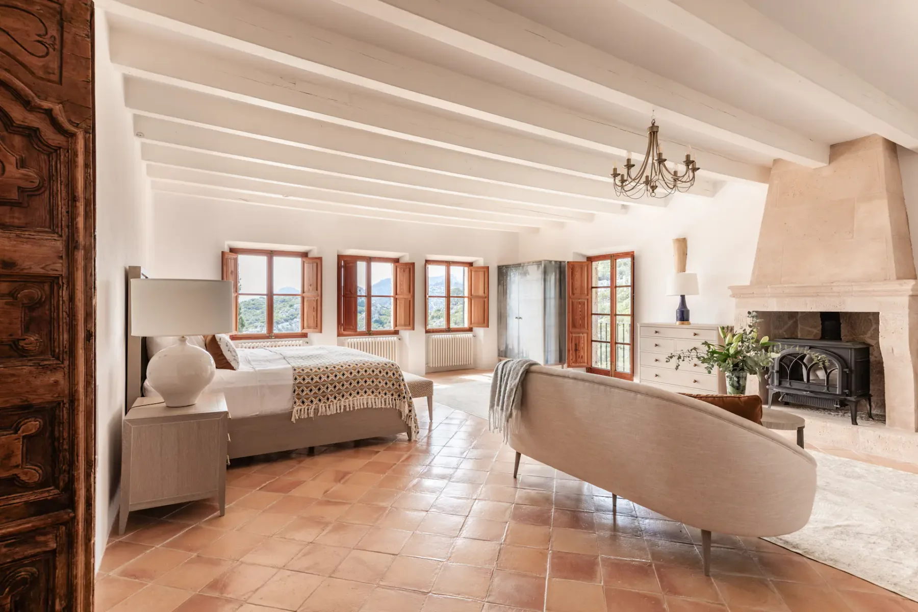 A bedroom with a bed, curved seating, and a fireplace.