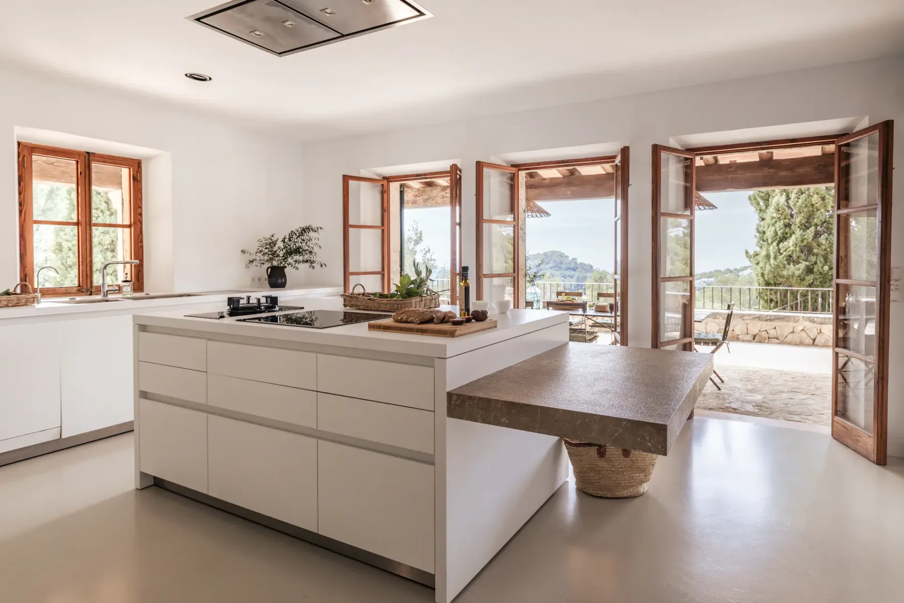 A bright kitchen opens onto a terrace through several large windows.