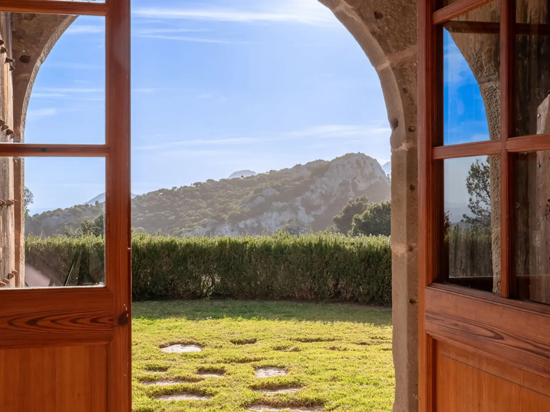 An arched doorway opens onto a grassy garden with a mountain beyond.