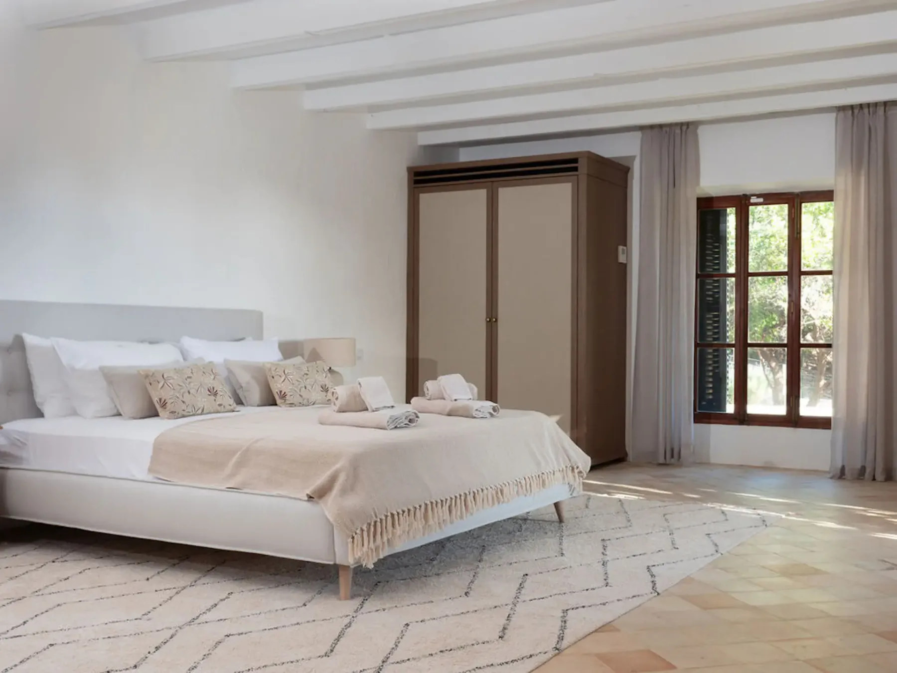 A bedroom with a large bed, a wardrobe, and a window.