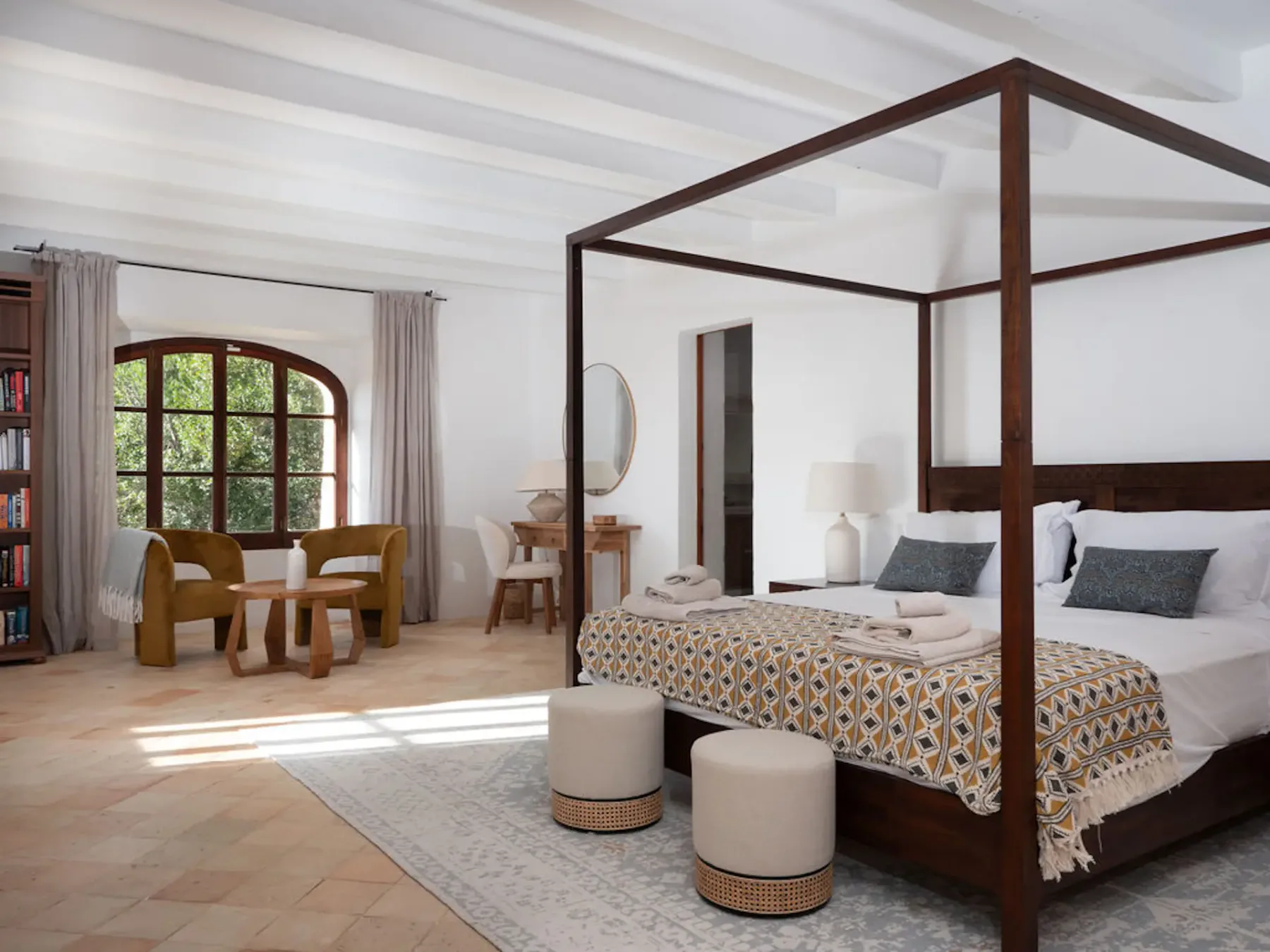 Bedroom with a four-poster bed and a small seating area by the window.