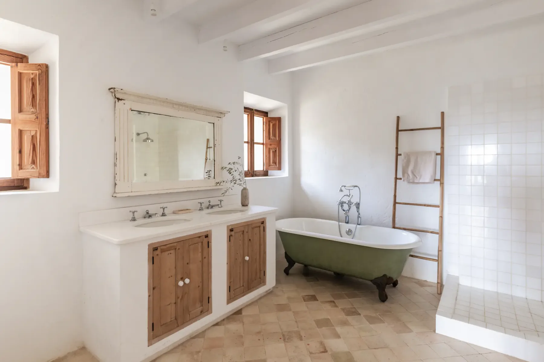 A bright bathroom with a wooden vanity and freestanding bathtub.